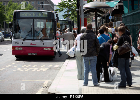 passengers queuing and boarding a bus at a bus stop during saturday shopping belfast northern ireland Stock Photo