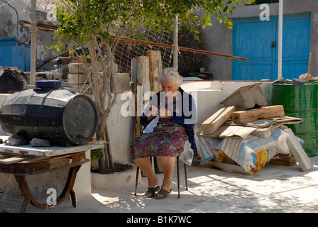 An old lady knitting in front of her house, Greece Stock Photo