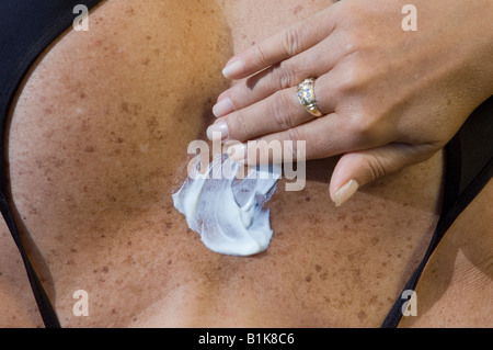 woman with freckles in bikini applying suntan lotion Stock Photo
