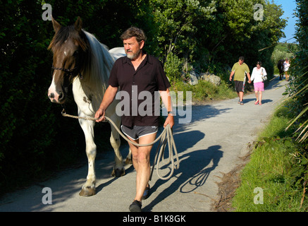 Man walking with his horse through middle town st martin's along one of the only roads on the island Stock Photo