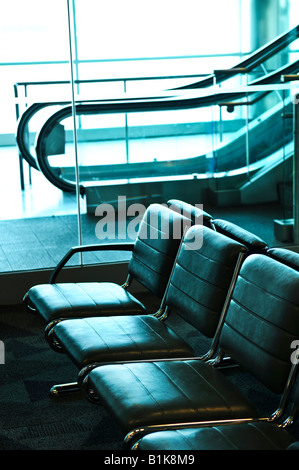 Row of chairs and escalator inside an airport Stock Photo