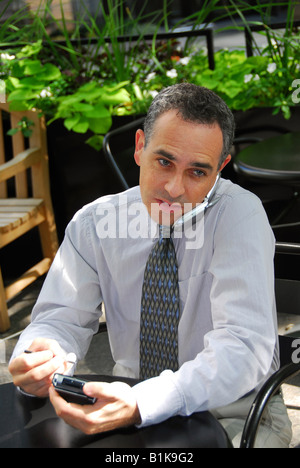 Portrait of a busy businessman in the city using pda and cell phone Stock Photo