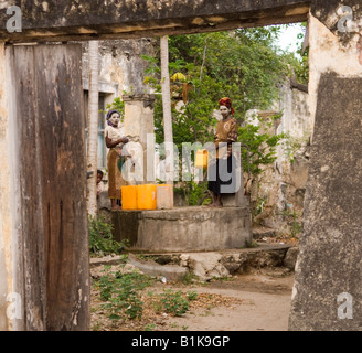 Two girls with white musiro mask drawing water from a well in Ibo, Mozambique Stock Photo