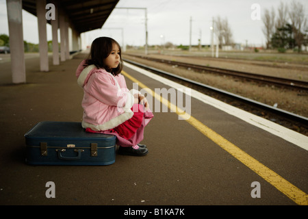 Girl aged four waits for train on platform at railway station Palmerston North New Zealand Stock Photo