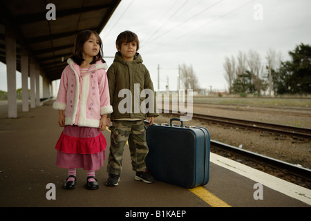 Boy aged six and sister aged four wait for train on platform at railway station Palmerston North New Zealand Stock Photo