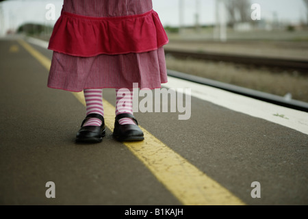 Girl aged four in pink skirt waits at on platform at railway station Stock Photo