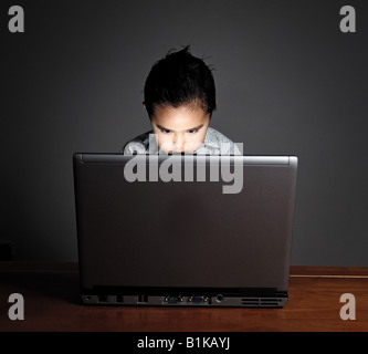Little boy using a laptop with a very concentrated look Stock Photo