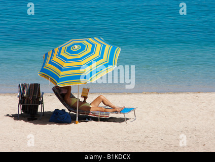 Mature woman relaxing and reading book on beach Stock Photo