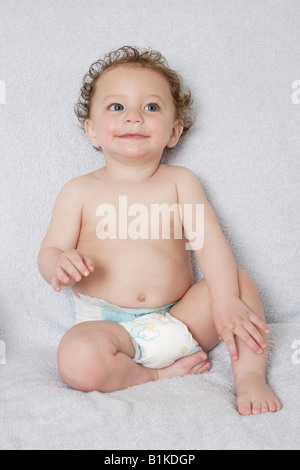 portrait little baby aged seven to ten months in disposable nappy sitting unaided Stock Photo