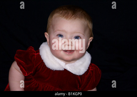 baby girl in CHRISTMAS red velvet dress with white collar Stock Photo