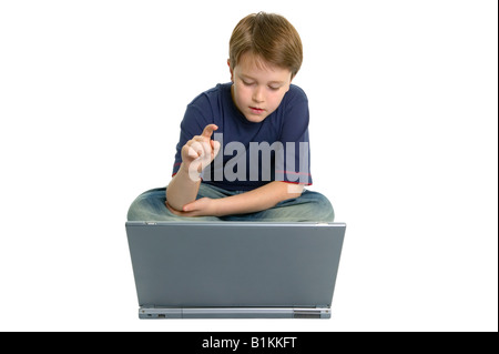 Boy sat crossed legged using a laptop computer isolated on a white background Stock Photo