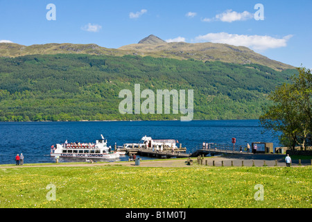 Cruise Loch Lomond passenger vessel approaching the pier at Tarbet Loch Lomond Scotland on a sunny day with Ben Lomond behind Stock Photo