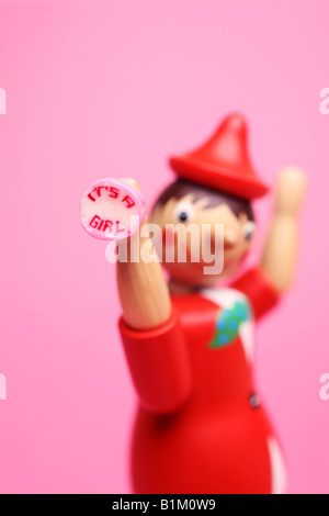 Pinocchio the wooden boy toy holding an 'it's a girl' rock sweet Stock Photo