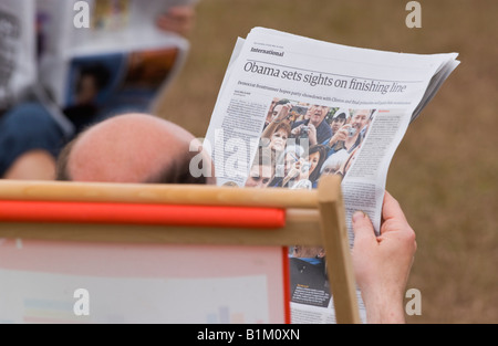 Bald man sat in deckchair reading newspaper at The Guardian Hay Festival 2008 Hay on Wye Powys Wales UK EU Stock Photo