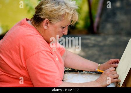 A woman in her late 50s sketches a picture she is preparing to paint outdoors at a painting workshop. Oklahoma City, Oklahoma, USA Stock Photo
