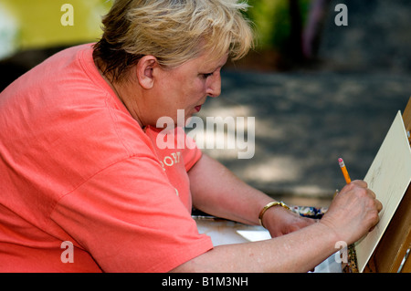 A woman in her late 50s sketches a picture she is preparing to paint outdoors at a painting workshop. Oklahoma City, Oklahoma, USA Stock Photo