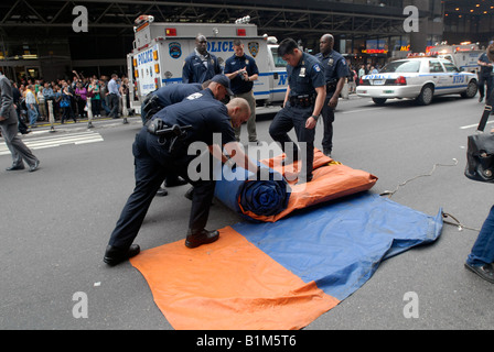 NYPD ESU officers roll up an airbag after a climber scales the New York Times building in New York Stock Photo