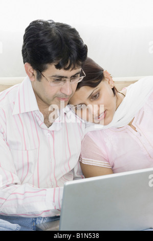 Close-up of a mid adult couple sitting together and looking at a laptop Stock Photo