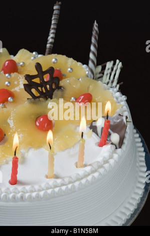 Chocolate Birthday Cake with lit candles on a white plate Stock Photo ...