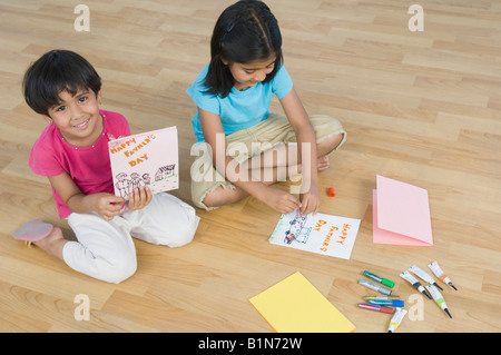 High angle view of two sisters making greeting cards and smiling Stock Photo