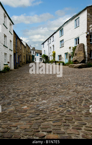 Looking up cobbled main street towards the Sedgewick Stone and the Sun Inn in Dent Yorkshire Dales National park near Sedbergh Stock Photo