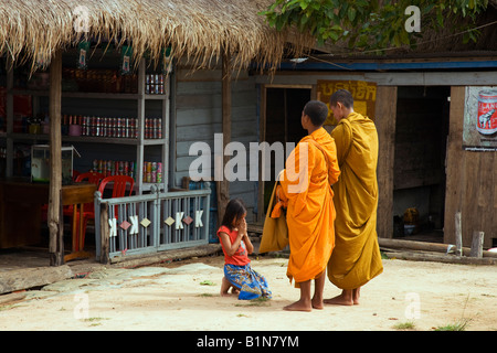 Buddhist monks go door to door each morning giving blessings and collecting alms; Phnom Khram, Cambodia Stock Photo