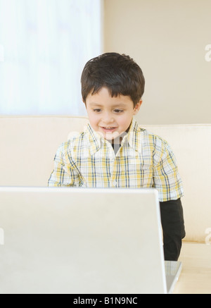 Boy standing at a table and using a laptop Stock Photo