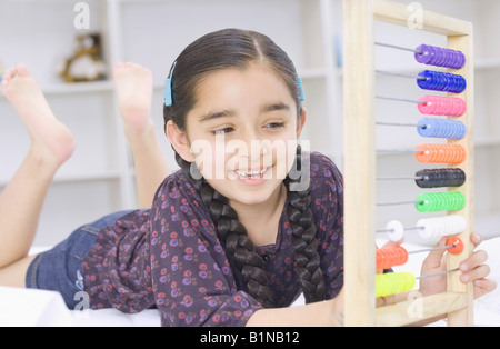 Girl lying on the bed and playing with an abacus Stock Photo