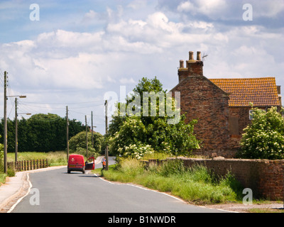 Post woman and red Post Office van on rural delivery round in East Yorkshire England UK Stock Photo