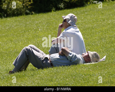 Old couple on the grass enjoying the summer sun. Stock Photo