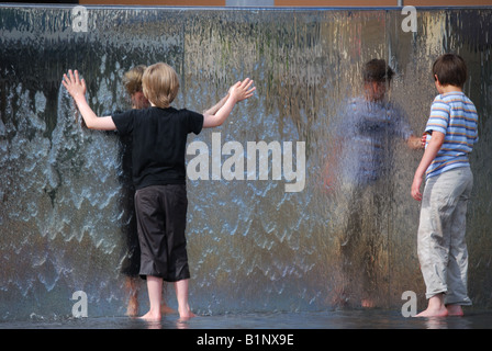 Boys playing in water fountain, At Bristol, Millennium Square, Harbourside, Bristol, England, United Kingdom Stock Photo