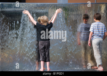 Boys playing in water fountain, At Bristol, Millennium Square, Harbourside, Bristol, England, United Kingdom Stock Photo