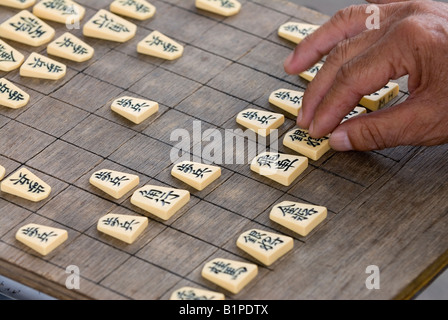 A man makes a move during a game of shogi which is similar to the Western game of chess. Stock Photo