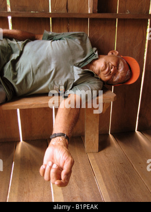 Old Brazilian man sleeping on bench in house Stock Photo