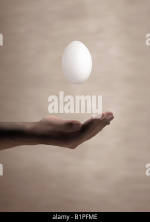 floating egg schwebendes fallendes Ei über einer Hand Stock Photo