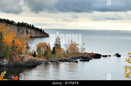 Rocky outcropping on the north shore of lake Superior on a cloudy fall morning with rocks trees water and clouds in the picture Stock Photo