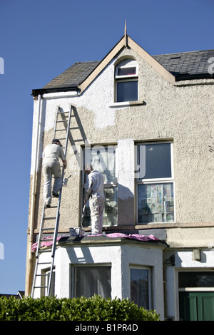 House Painters: Two house painters apply a fresh coat of white paint to a row house Stock Photo
