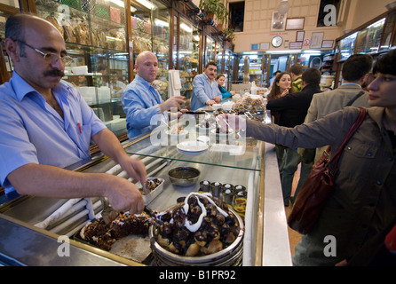Inci For profiterole lovers: A clerk cuts into the famous chocolate dessert in this  bakery for sweet chocolate delights Stock Photo