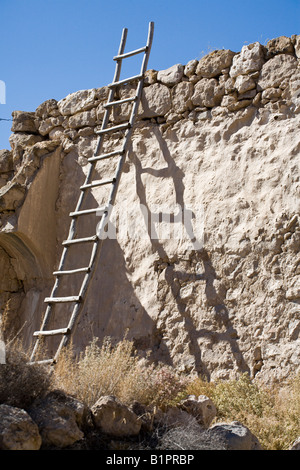 Ladder and Wall. A roughly constructed wooden ladder leaned against a partially plastered stone wall in the tiny village Stock Photo