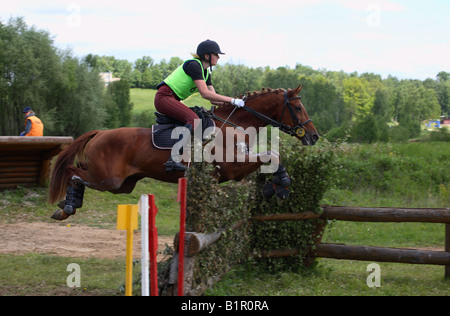 Young lady rider wearing a riding hat and a body protector is galloping on back of a purebred horse at autumn Stock Photo