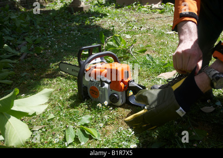 Man in full protective STIHL clothing putting chainsaw gloves on before operating his power tool