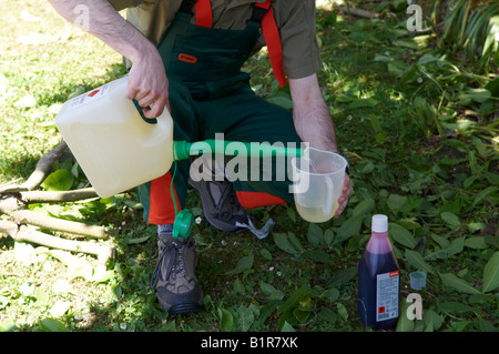 Man in full protective STIHL clothing filling a measuring container with petrol prior to mixing in oil for his power tools