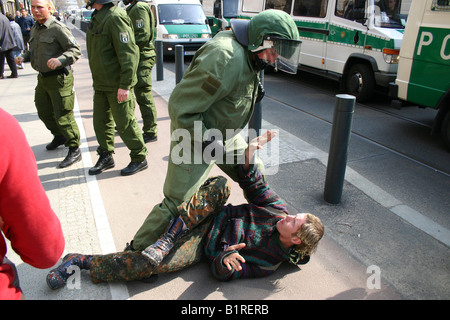 Police officer threatening a punk lying on the ground with his fist, Berlin, Germany, Europe Stock Photo