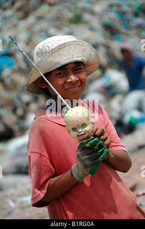 Child rummaging through a garbage dump finds a dolls head on the Stung Meanchey Municipal Garbage Dump in the south of Cambodia Stock Photo
