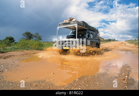 Land Rover driving through a puddle left by large amounts of rain near Omaruru, Namibia, Africa Stock Photo