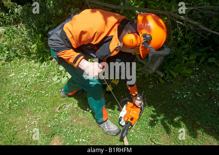Man in full protective STIHL power tool clothing starting his chainsaw MS 180