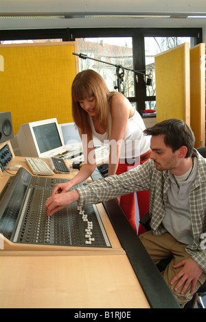 Young woman and engineer working on a mixer unit of a recording studio Stock Photo