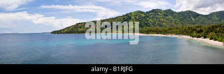 Palm trees behind a quiet bay and beach in front of a coral reef, fishing boats pulled onto the beach, Senggigi, Lombok Island, Stock Photo