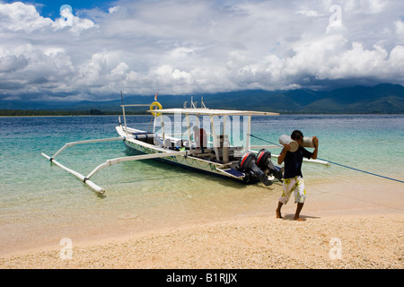 Man unloading diving tanks from a diving boat, Trawangan Island, Lesser Sunda Islands, Indonesia, Asia Stock Photo