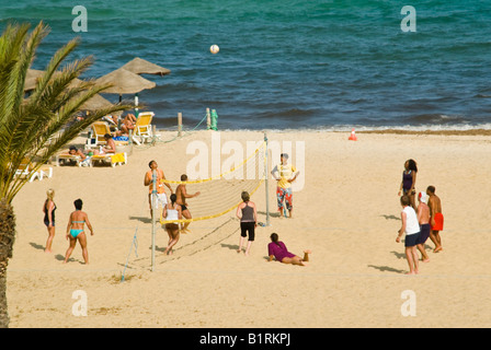 Horizontal elevated view of people playing a game of beach volley ball on a bright sunny day Stock Photo